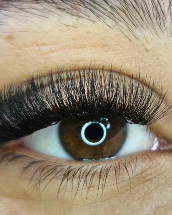 Close-up van een bruin oog met een donkere, volle set wimperextensions