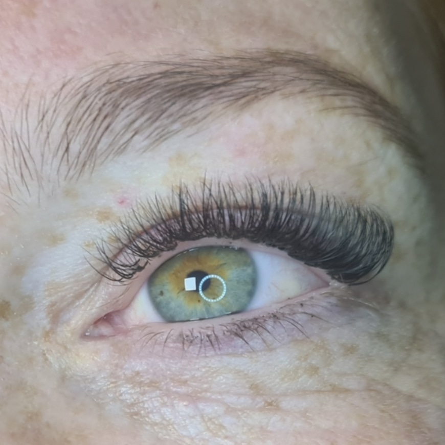 Close-up van een groen oog met een volle set wimperextensions