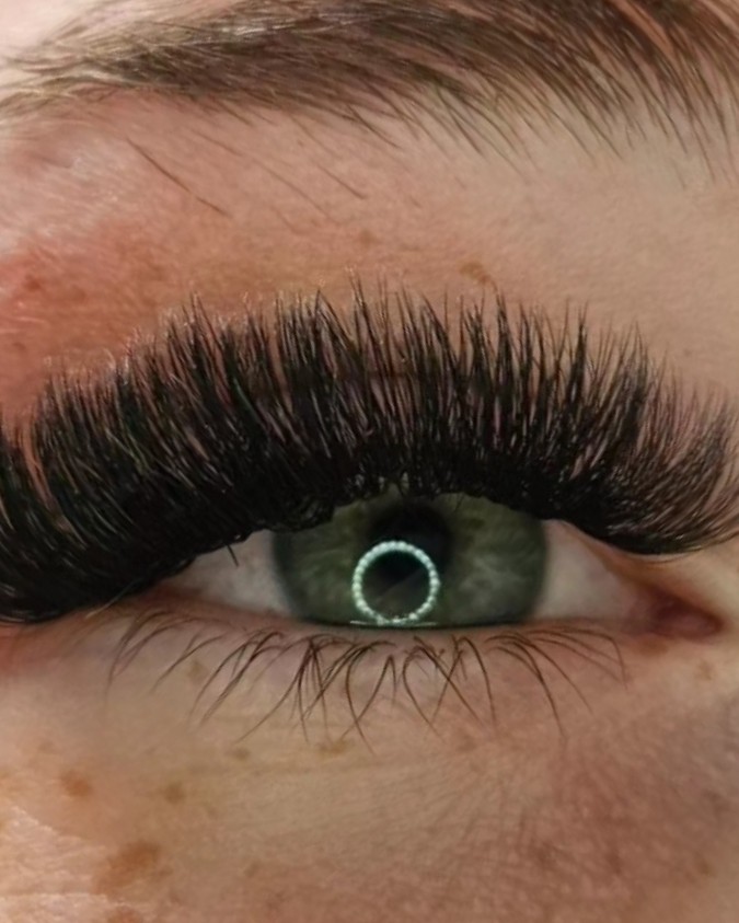 Close-up van een groen oog met een lange, volle set wimperextensions
